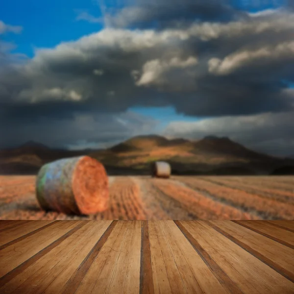 Landscape of hay bales in front of mountain range with dramatic — Stock Photo, Image