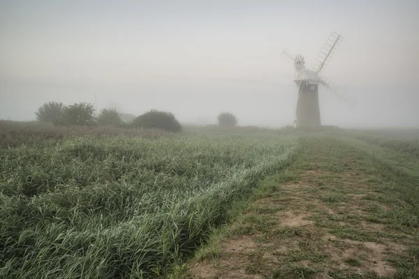 Velho moinho de vento na paisagem nebulosa do campo na Inglaterra — Fotografia de Stock