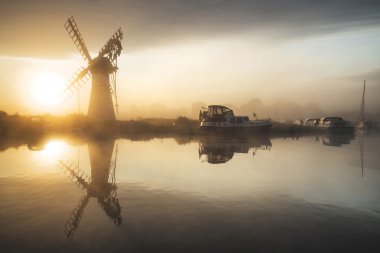 Stunnnig landscape of windmill and calm river at sunrise on Summ clipart
