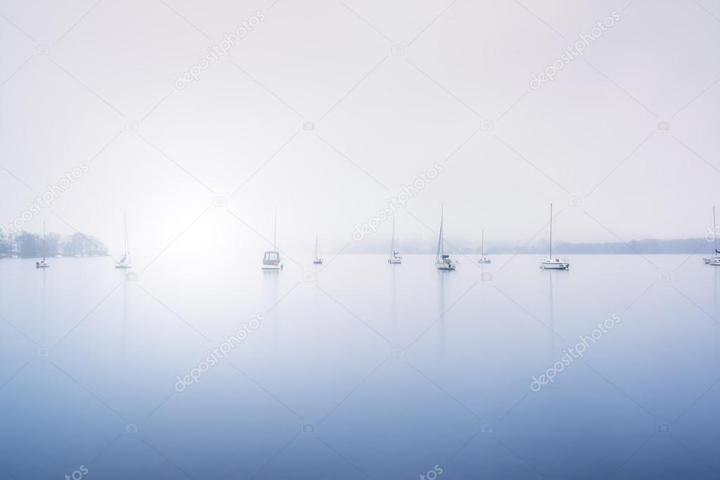 Sailing boats foggy morning on Lake Windermere in Lake District 