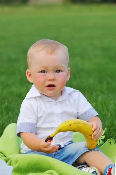 Little boy sits with banana — Stock Photo, Image