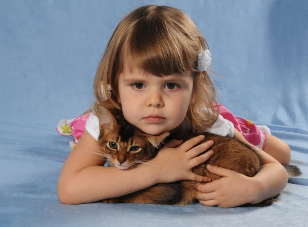 Little girl lying with somali kitten ruddy color — Stock Photo, Image