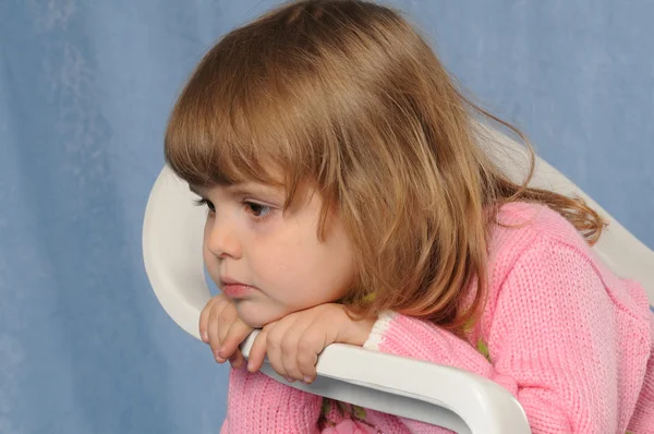 Petite fille triste sur chaise blanche au studio portrait — Photo