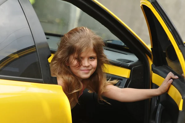 Chica bonita mirando hacia fuera de coche deportivo amarillo — Foto de Stock