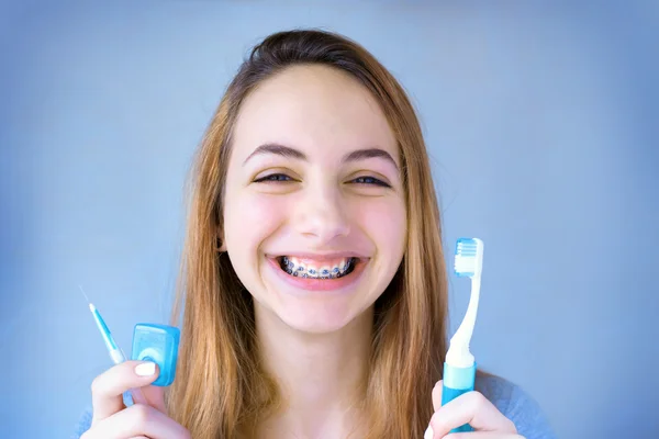 Menina sorridente bonita com retentor para dentes escovação dentes  . — Fotografia de Stock