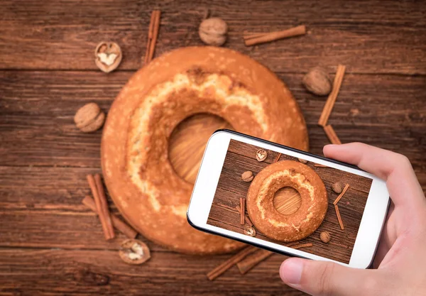Ruce s Foto domácí koláč s vlašskými ořechy s smartphone. — Stock fotografie
