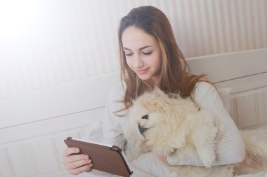 Köpeğini tablet ile yatakta kızla.