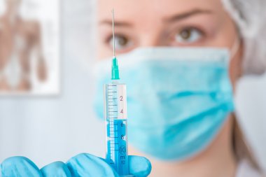 Hemşire ya da kadın doktor elinde iğne tutuyor. .