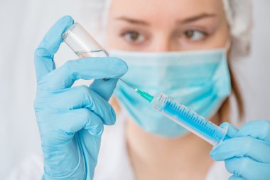 Hemşire ya da kadın doktor elinde iğne tutuyor. .