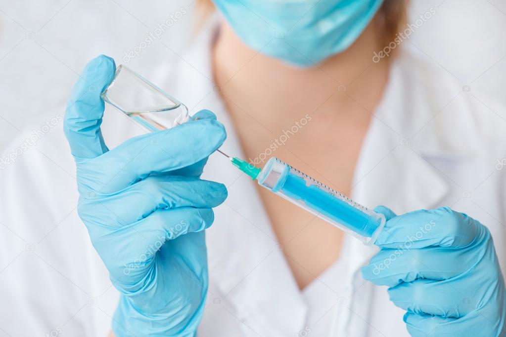 Nurse or female doctor holding an injection needle .