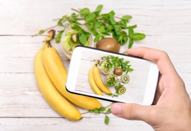 Eller fotoğraf tatlı meyve ve krem peynir ile cam alarak smartphone ile jar.