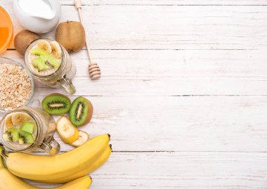 Yulaf ezmesi, muz, kivi ahşap arka plan üzerinde cam kavanozlara smoothies.