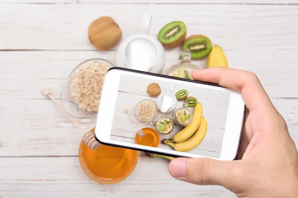 Händer med foto smoothies med havregryn med smartphone. — Stockfoto