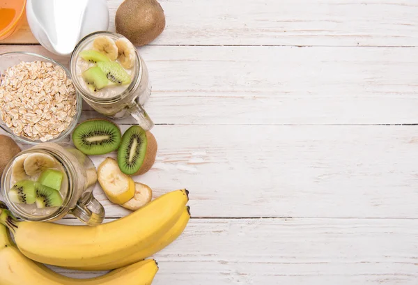 Smoothies mit Haferflocken, Banane, Kiwi in Glasgläsern auf Holzgrund. — Stockfoto