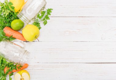 Smoothies ile havuç, elma, limon, maydanoz cam kavanozlar ahşap bir arka plan üzerinde. 