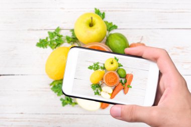 Eller fotoğraf smoothies havuç, elma, limon, maydanoz ile smartphone ile alarak.