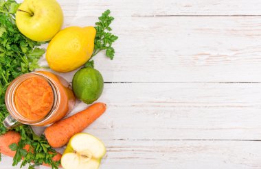 Smoothies ile havuç, elma, limon, maydanoz cam kavanozlar ahşap bir arka plan üzerinde. 