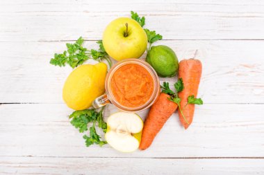 Smoothies ile havuç, elma, limon, maydanoz cam kavanozlar ahşap bir arka plan üzerinde. 