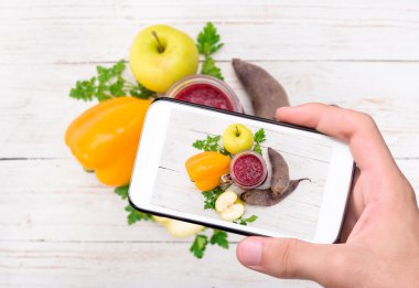 Eller fotoğraf smoothies pancar, biber, elma, limon, maydanoz ile smartphone ile alarak.