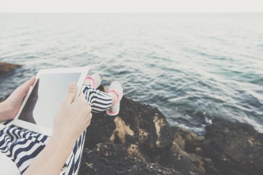 Deniz kenarında bir dijital tablet kullanan kız.