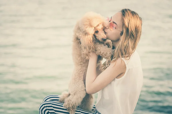 Giovane ragazza sta riposando con un cane sul mare . — Foto Stock