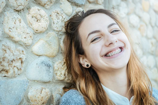 Belle fille souriante avec un dispositif de retenue pour les dents repose sur le plein air  . — Photo