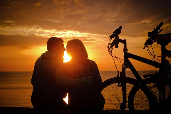 Par av cyklister på stranden vid solnedgången. — Stockfoto