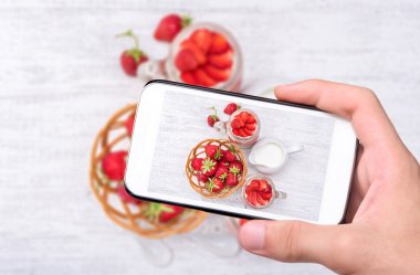 Eller fotoğraf tatlı çilek ve krem peynir ile cam alarak smartphone ile jar.