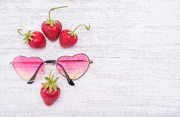 Ripe strawberries with sunglasses on a wooden background. — Stock Photo, Image