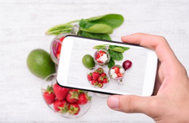 Ispanak, çilek ve peynir ile smartphone ile fotoğraf salata alarak eller.