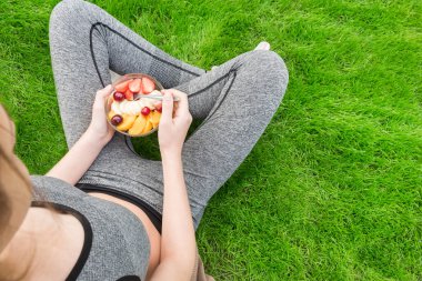 Young girl eating a fruit salad after a workout .