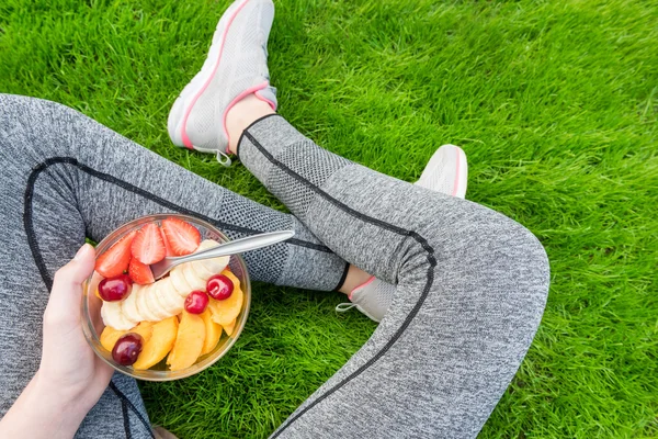 Young girl eating a fruit salad after a workout . — Stok fotoğraf