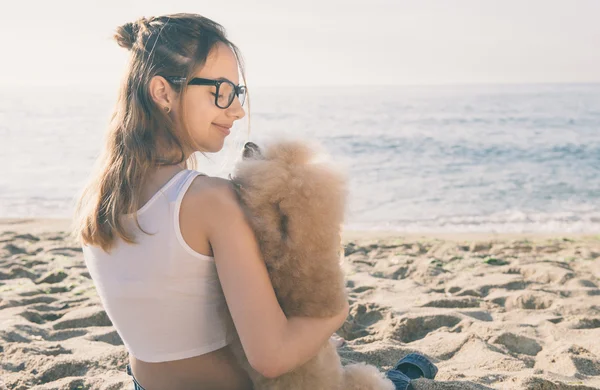 Ung flicka vilar med en hund på havet. — Stockfoto