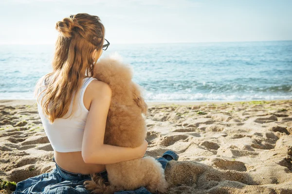 Ung flicka vilar med en hund på havet. — Stockfoto