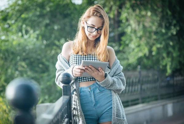 Fille en utilisant une tablette numérique à l'extérieur . — Photo