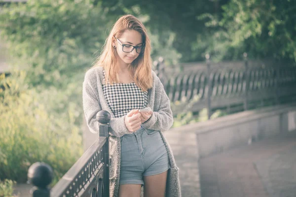 Fille à l'aide d'un téléphone portable à l'extérieur . — Photo