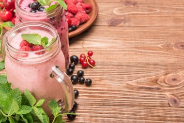 Smoothies ahşap arka plan üzerinde cam kavanozlara taze çilek ile. 