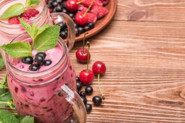 Smoothies ahşap arka plan üzerinde cam kavanozlara taze çilek ile. 