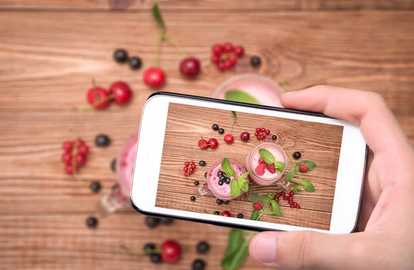 Руки делают фото коктейли со свежими ягодами в стеклянных банках со смартфоном . — стоковое фото