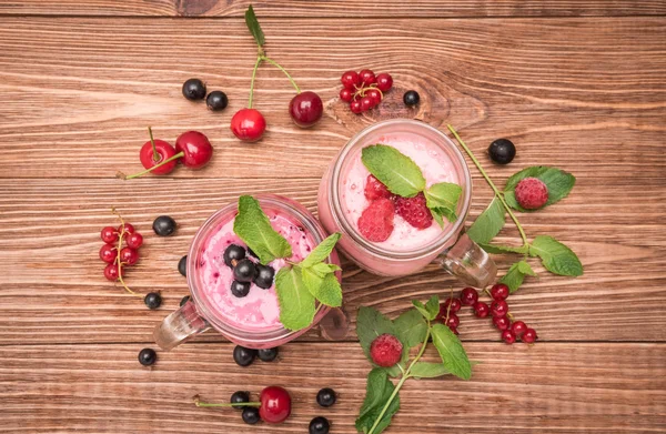 Smoothies ahşap arka plan üzerinde cam kavanozlara taze çilek ile. — Stok fotoğraf