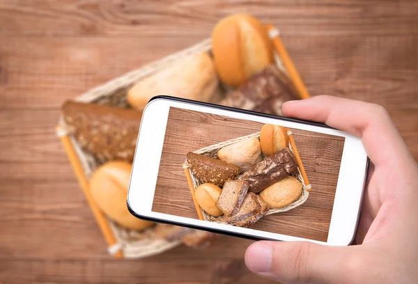 Руки делают фото выпечки хлеба со смартфоном . — стоковое фото