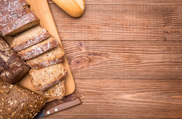 Auswahl an gebackenem Brot auf Holztischhintergrund. — Stockfoto