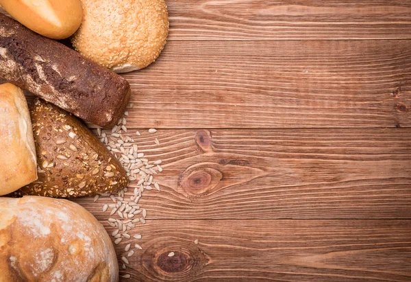 Sortiment av bakat bröd på träbord bakgrund. — Stockfoto