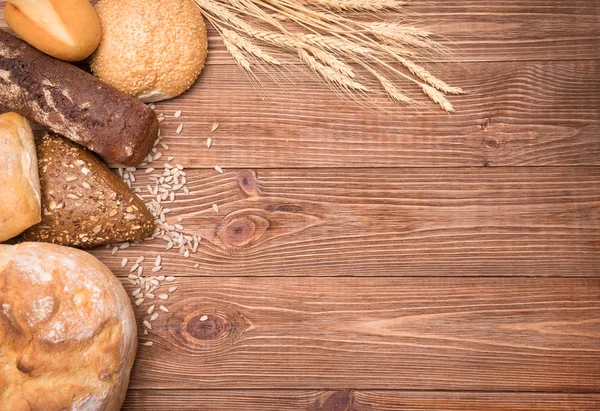 Sortiment av bakat bröd på träbord bakgrund. — Stockfoto