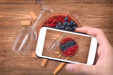 Eller fotoğraf şarap cam çilek ile smartphone ile alarak.