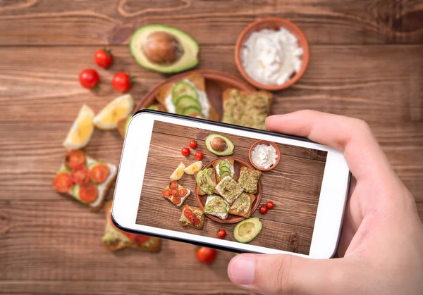 Manos tomando foto sándwich vegetariano casero con teléfono inteligente . —  Fotos de Stock
