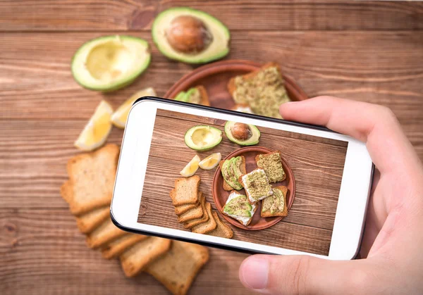 Hands taking photo homemade avocado sandwich with smartphone. — Stock Photo, Image