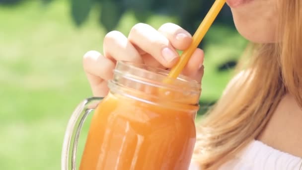 Vacker ung flicka drycker saft från en glas mugg. — Stockvideo