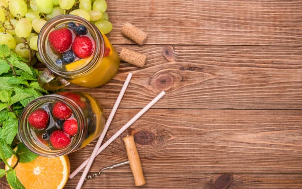 Hemgjord vit vin sangria med färska bär på ett träbord. — Stockfoto