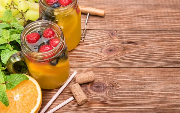 Sangria de vinho branco caseiro com bagas frescas em uma mesa de madeira . — Fotografia de Stock